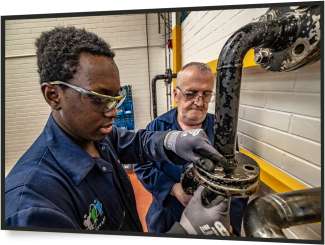 young and older male engineers adjusting pipe