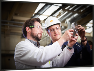 2 male engineers in PPE looking at a piece of metal