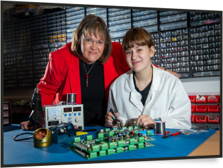 an older woman and young girl smiling at the camera in front of electric controls