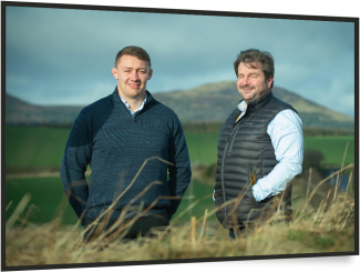young male and older male farmers standing in field