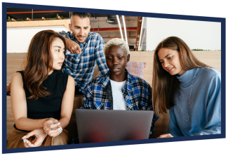 Four young people gathered round a laptop, looking at the screen